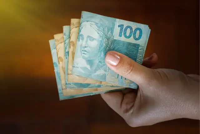 Mão segurando notas de real de um empréstimo para negativado liberado na hora