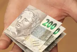 notas de 200 reais na mão de uma pessoa