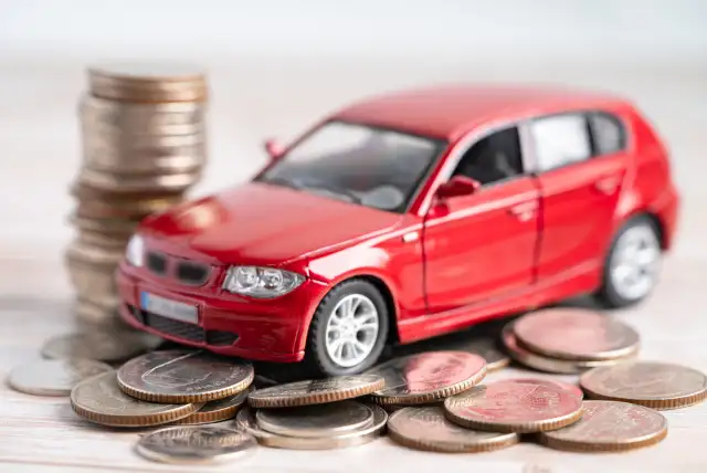 Carro de brinquedo em cima de moedas para exemplificar o empréstimo com garantia de veículo