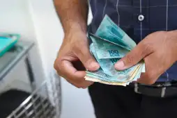 um homem com notas de real nas mãos depois de pedir um empréstimo pessoal